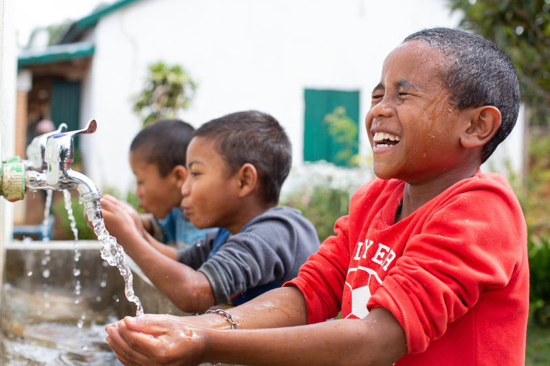 Children washing their faces with clean water at a school handwashing station