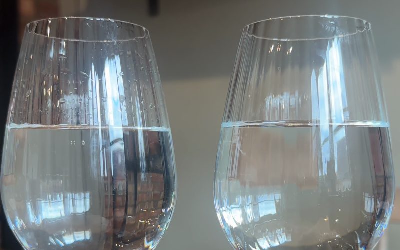 Deux verres d'eau côte à côte, l'un non filtré et l'autre filtré par Flowpure